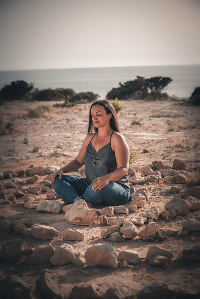 Una mujer está meditando en la playa.